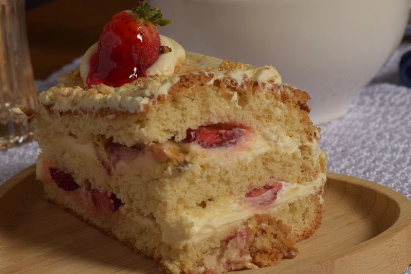 Fatia de bolo com morangos e creme sobre prato de madeira