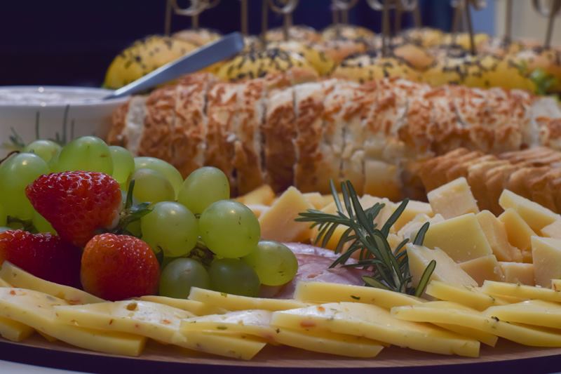 Mesa de bufê com morangos, uvas, queijos e pães