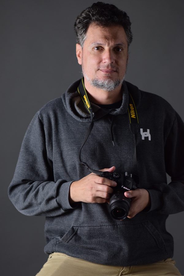 Denis Souza, fotógrafo, segurando sua câmera